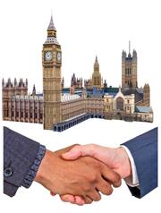 Two peoples hands shaking each other under a picture of the Houses of Parliament