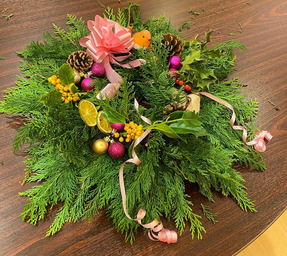 Another handmade Christmas wreath with ribbon and real foliage on a table top