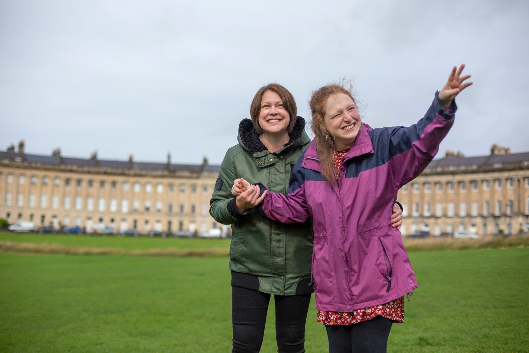 Two women standing on a green with the famous Bath crescent terrace houses behind them