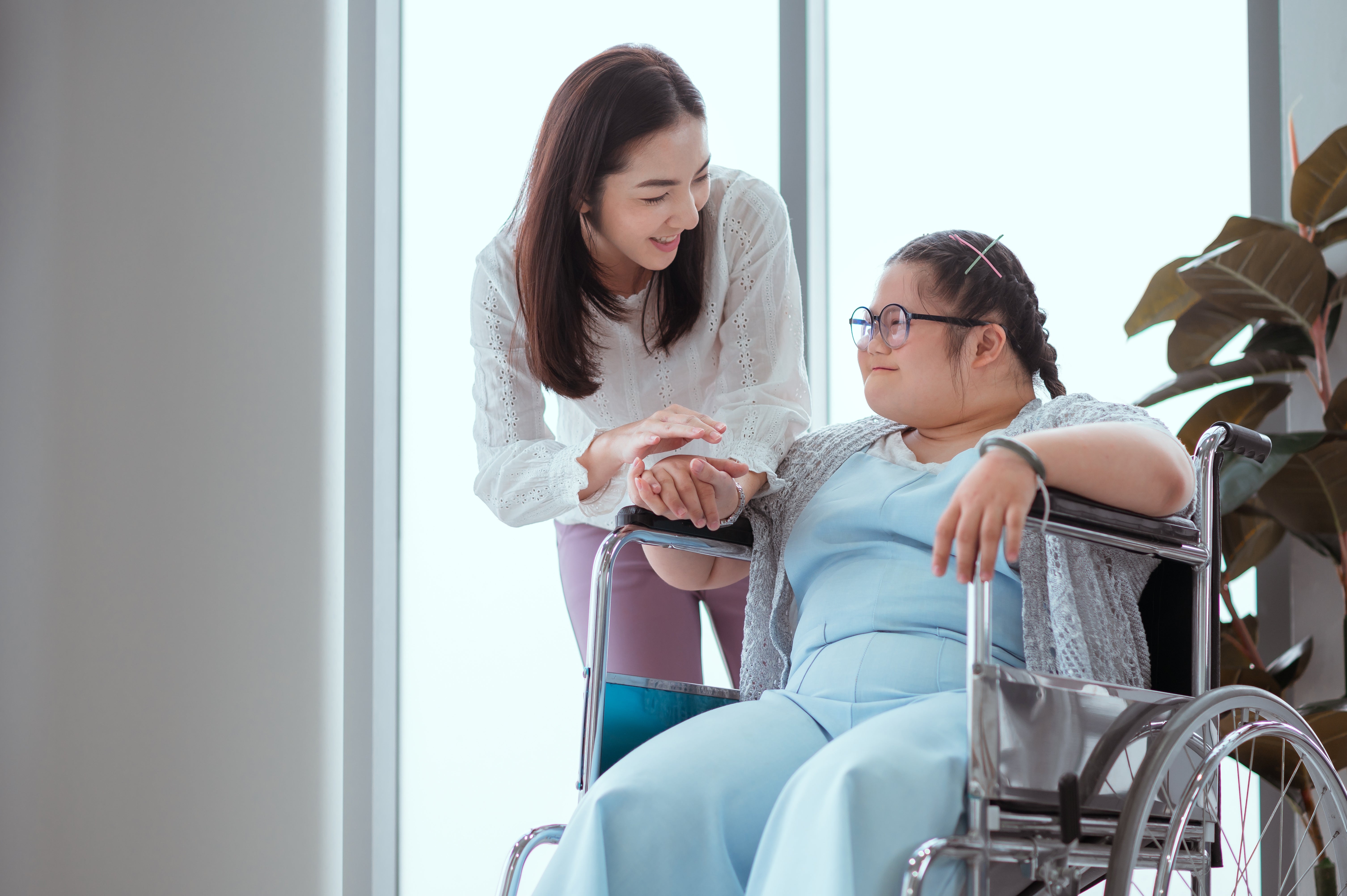 A young woman in a wheelchair with a care worker