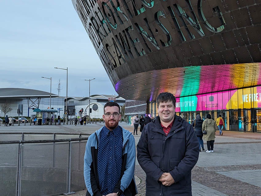 Two men stand outside the Wales Millennium Centre 