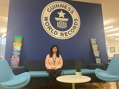 A woman with long dark hair sitting in front of a blue wall with a Guinness World Records logo