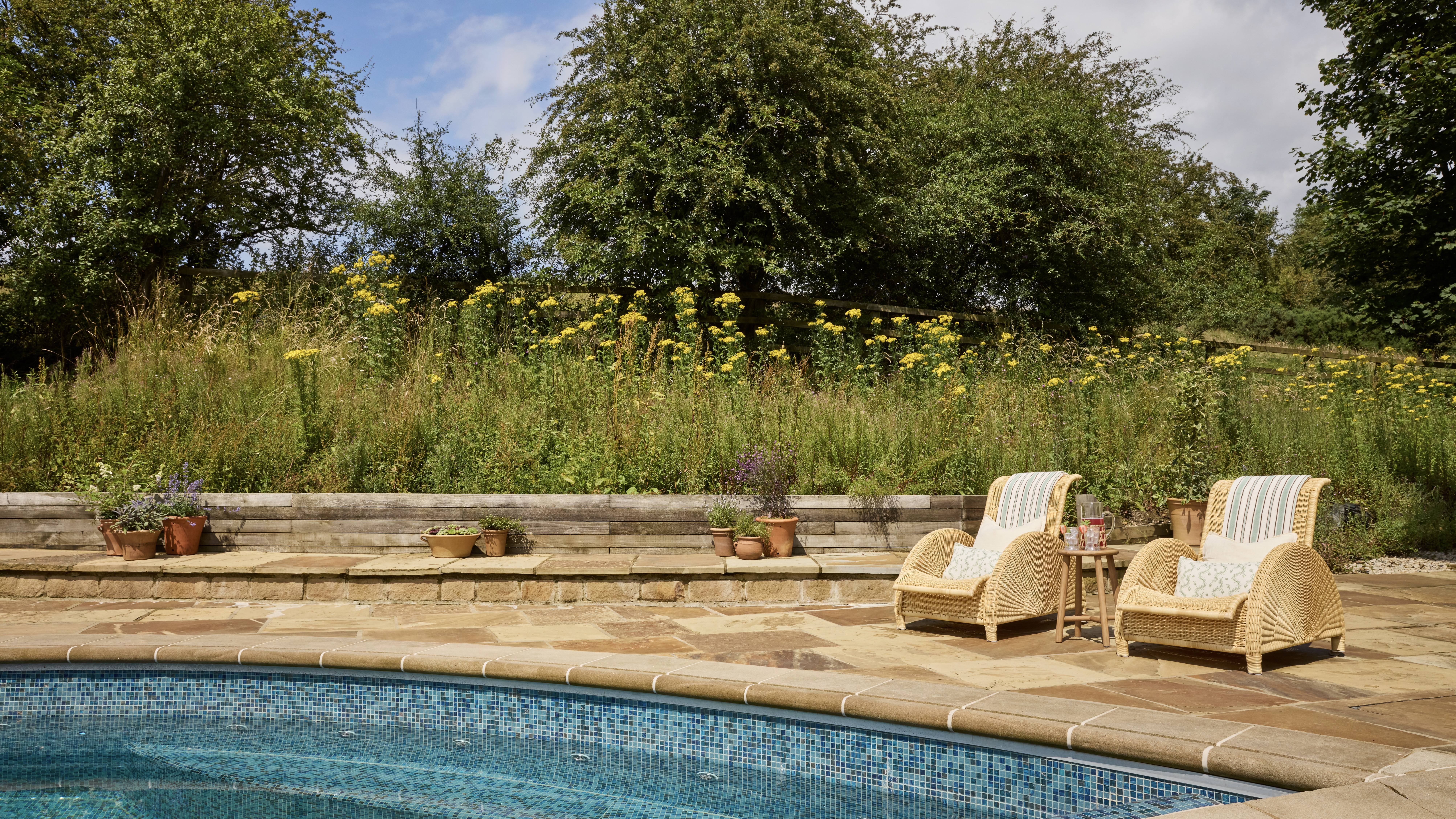 Outdoor swimming pool with two garden chairs on the side