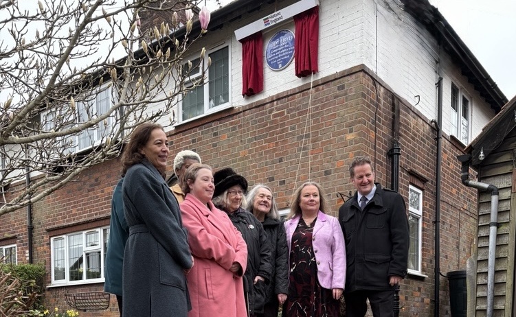 A group of people including Mencap's CEO, outside the house where a blue plaque is installed for the Mencap founder Judy Fryd