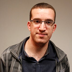 Man, Sam Jefferies, with short hair wearing glasses, looking into camera.
