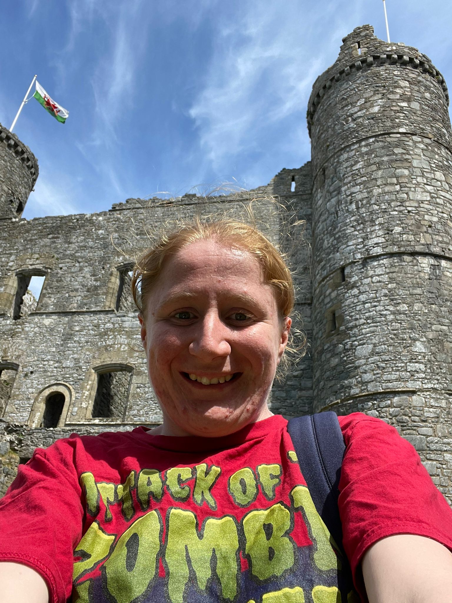 A woman in a red T-Shirt takes a selfie in front of a castle
