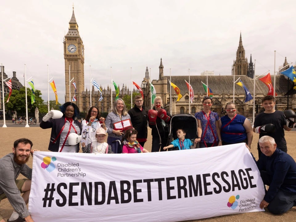 A group of people hold a sign reading "Disabled Children's Partnership #SENDABETTERMESSAGE"