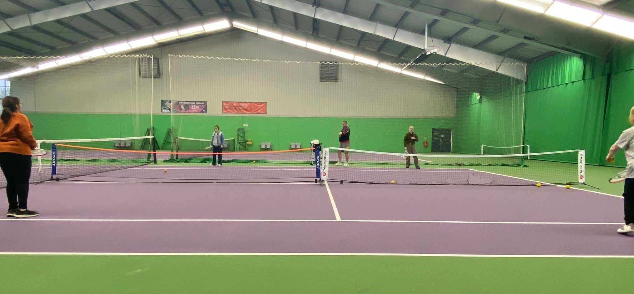People playing tennis on an indoor court