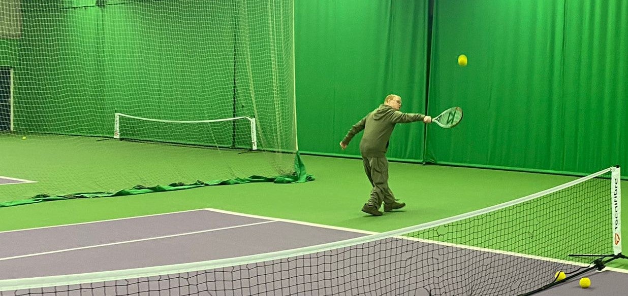 Man serving in tennis on an indoor court