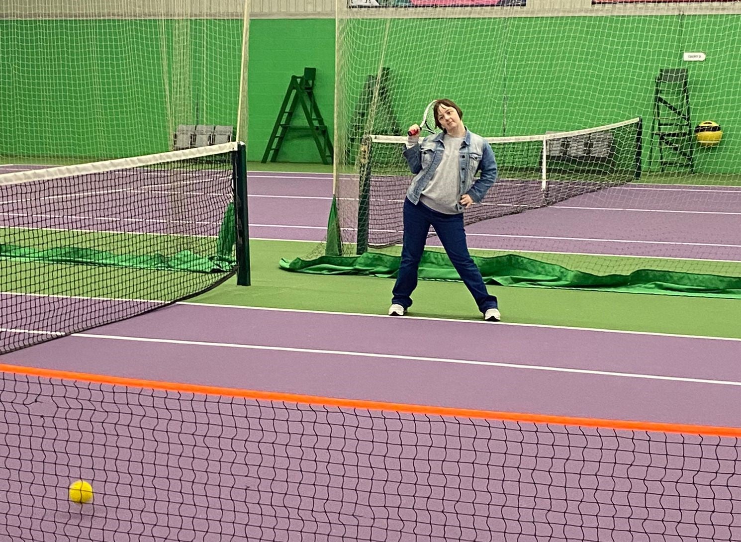 Woman posing with tennis racquet on an indoor court 