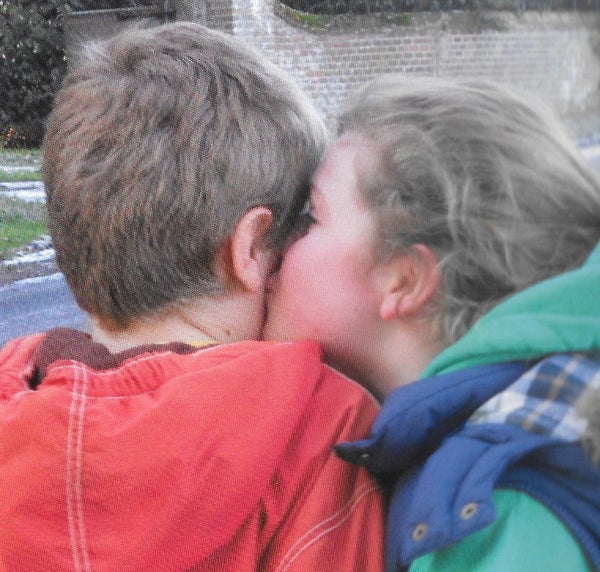 Sister kissing her brother on the cheek.