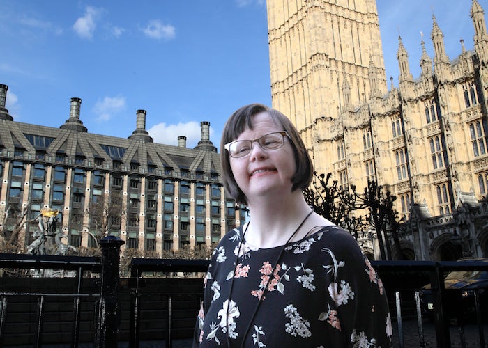 Woman, Tessa, with short hair and glasses, stood outside Houses of Parliament in London.