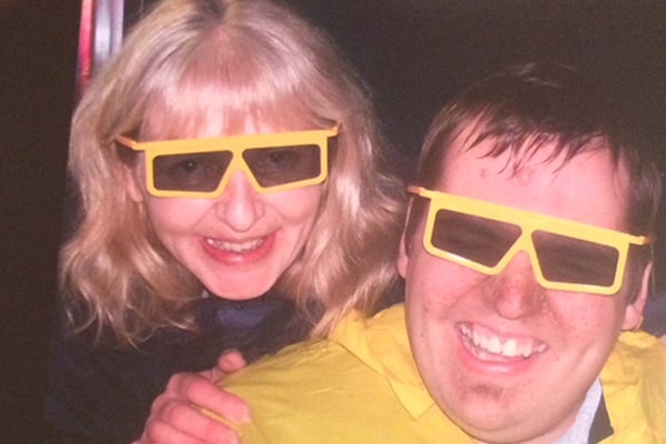 Mother and son, Sue and Nick Jones, stood together smiling wearing yellow rimmed glasses