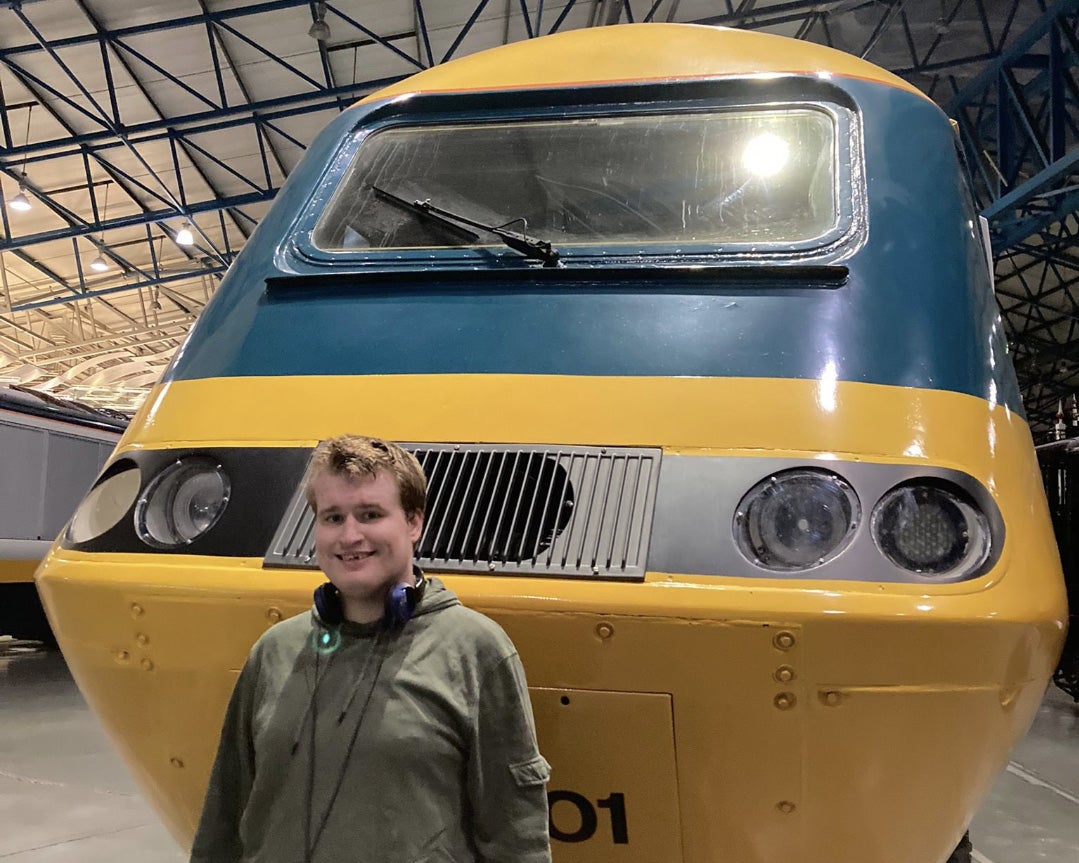 Elliot stands in front of a train on display