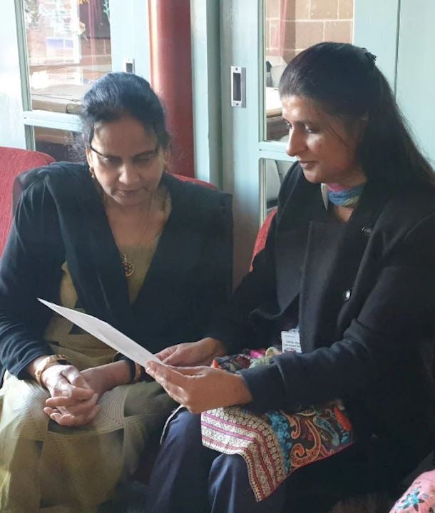 Zahida and Parveen sit together reading a piece of paper