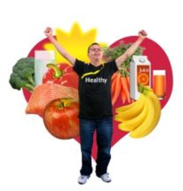 A man with his hands in the air standing in front of a heart shape full of fruit and vegetables