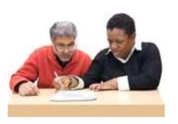 a man helping another man to fill out a form