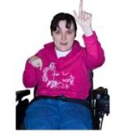 A woman in a wheel chair with her hand raised to ask a question