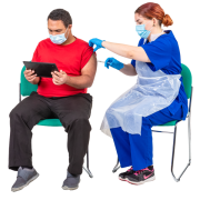 A nurse sitting down giving a man, who is also sitting down and holding a tablet, an injection