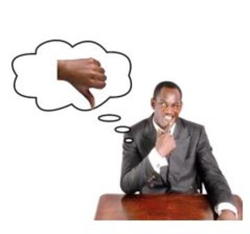 A man sitting at a desk thinking with a thought bubble over his head with a thumbs down picture inside it.