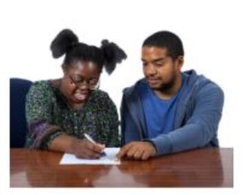 A woman writing a letter with a man helping her