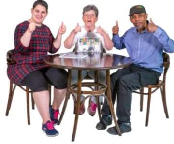 Three people sitting at a table with their thumbs up
