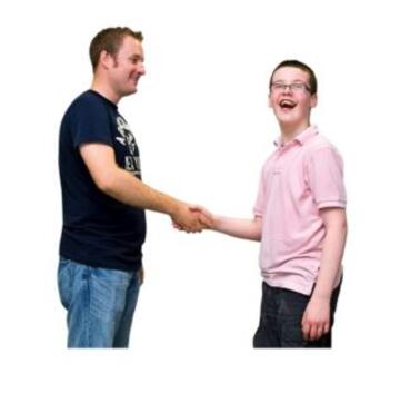 A man shaking a young mans hand. Both are smiling
