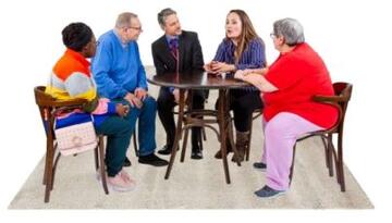 A group of people sitting around a meeting desk talking