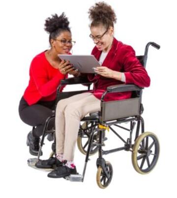 A woman in a wheelchair being shown a tablet by a support worker.