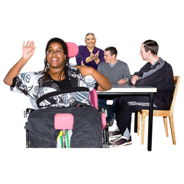 A woman in front of a table where people are meeting with one hand raised and the other pointing at herself