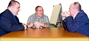 A group of people at a meeting desk with a flip chart beside the desk