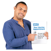 A man holding a letter from the NHS which says 'Your vaccine appointment'.