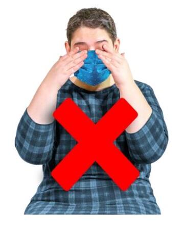 A red cross over a picture of a woman touching her face when wearing a face covering