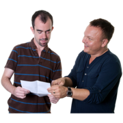 A man smiling and showing another man a leaflet whilst explaining it to him