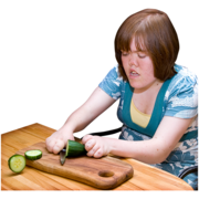 A woman chopping a cucumber on a wooden chopping boarrd
