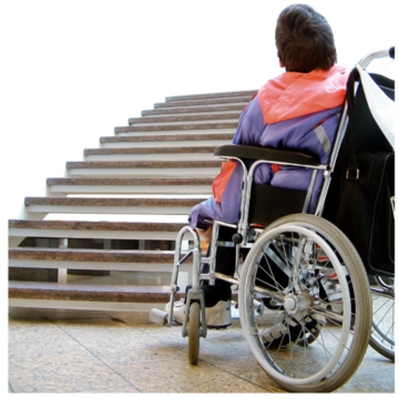 A person in a wheelchair at the bottom of a flight of stairs