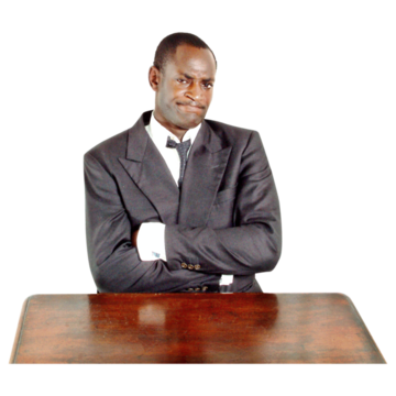 A man in a suit who has his arms folded at a desk and looks unhappy