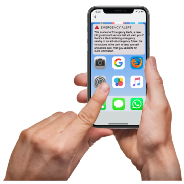 A mobile phone with the emergency alert test message on the screen.