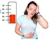 A lady holding her stomach and her head.  Behind her is a thermometer showing between 55 and 60 degrees.ng