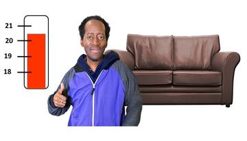 A man with his thumb up.  Behind him is a sofa and a thermometer.