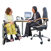 A woman in a wheelchair is talking to her doctor at her desk
