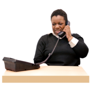 A woman sitting at a desk and speaking on a telephone.