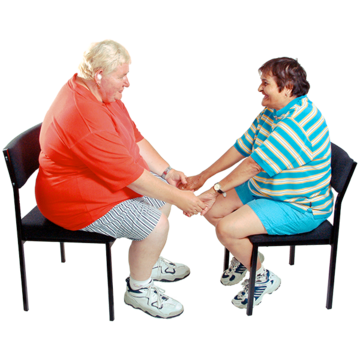Two women sit facing each other and hold hands