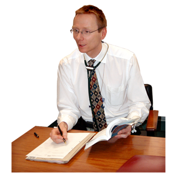 A doctor with a stethoscope around his neck is sitting at a desk writing a report