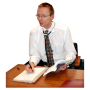 A doctor with a stethoscope around his neck is sitting at a desk writing a report