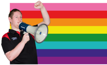 A  man with his fist in the air and holding a loudspeaker in front of the old version of the LGBT+ flag