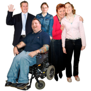 Left to right: A man in a suit, waving. A woman in a denim jacket. A woman in a red cardigan, with her arms round a girl in a pink top. A man in a wheelchair.
