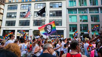 A crowd of people holding LGBT+ flags in a New York street