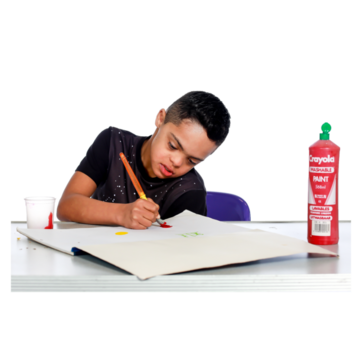 A young boy paining on a piece of paper with some green paint and a brush
