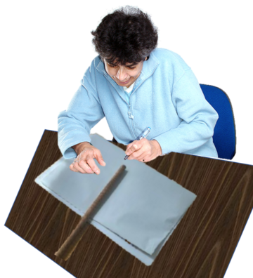 A young man, sitting at a desk, has turned his placard over and is fixing a stick to the back of it